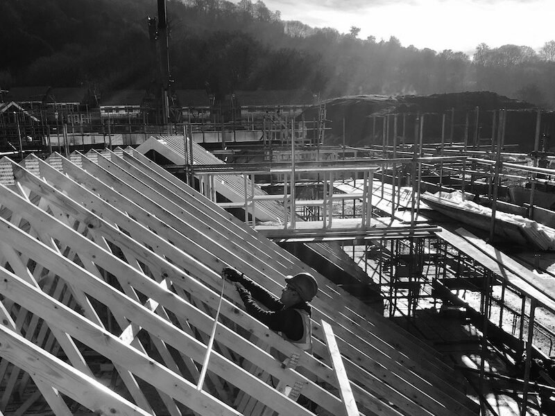 offsite construction - erector constructing timberframe kit on large housing development